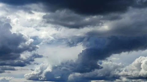 Dramatic dark storm clouds and white cumulus in blue sky Foto stock