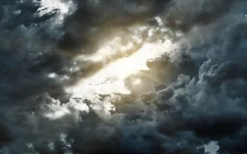 Dramatic dark storm clouds with bright sun rays breaking through the overca.. Stock Photos