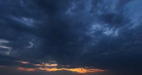 Dramatic dark storm clouds gather above an orange sunset Foto stock