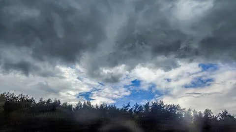 Dramatic dark storm clouds gather over a dense forest canopy Foto stock