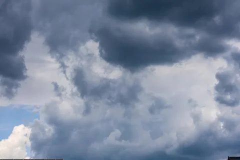 Dramatic dark storm clouds gathering in the sky above rooftops Stock Photos