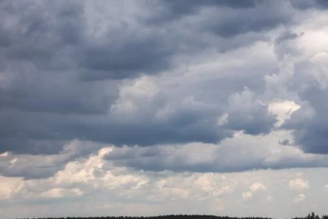 Dramatic dark storm clouds gathering over a distant forest horizon Stock Photos