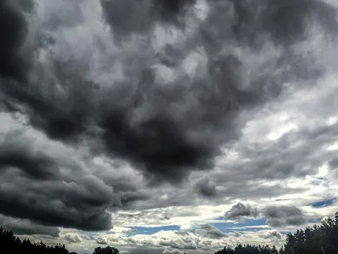 Dramatic dark storm clouds gathering over a distant tree line horizon Foto stock