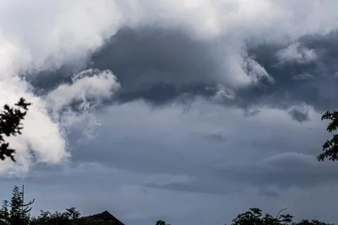 Dramatic dark storm clouds gathering ominously in the sky above treetops Stock Photos