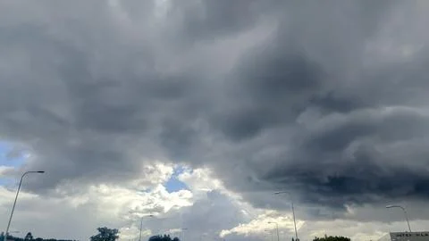 Dramatic dark storm clouds gathering over a highway with streetlights Fotos Stock