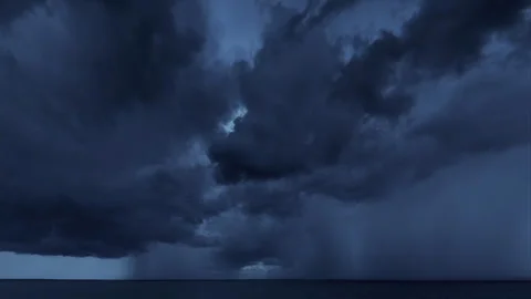 Dramatic dark storm clouds moving over the ocean horizon at night 库存影片 331951329