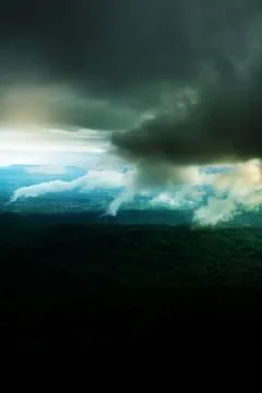 Dramatic dark storm clouds over a green forest. Stock Photos