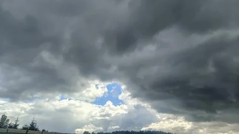 Dramatic dark storm clouds parting to reveal a bright blue sky and sunlit c.. 写真素材
