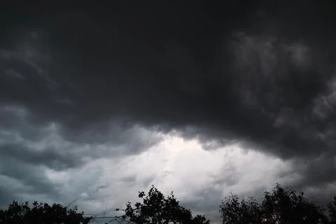 Dramatic dark storm clouds in sky over forest silhouette before rain close up Stock Photos