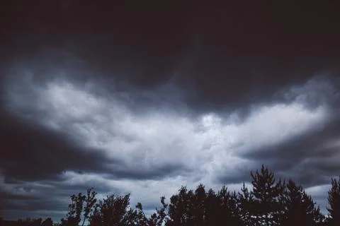 Dramatic dark storm clouds in sky over forest silhouette before rain close up Stock Photos