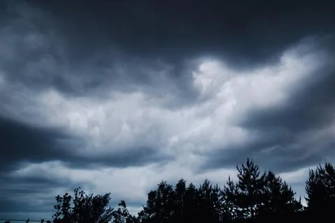 Dramatic dark storm clouds in sky over forest silhouette before rain close up Stock Photos