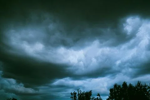 Dramatic dark storm clouds in sky over forest silhouette before rain close up Stock Photos