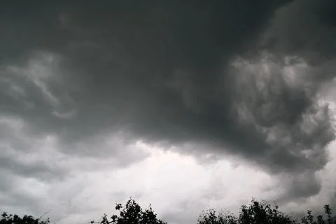 Dramatic dark storm clouds in sky over forest silhouette before rain close up Foto stock