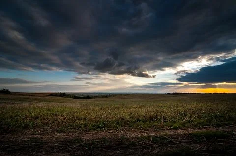 Dramatic dark storm sky with clouds at sunset over the field with stubble  Stock Photos