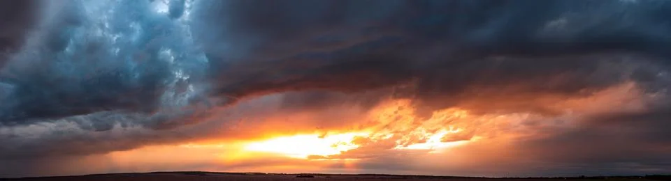 Dramatic dark sunset. Panorama of dark rain clouds in the evening Stock Photos