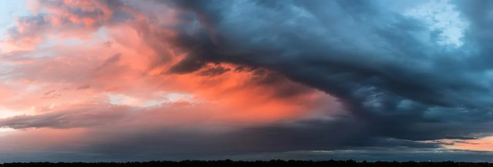 Dramatic dark sunset. Panorama of dark rain clouds in the evening Stock Photos