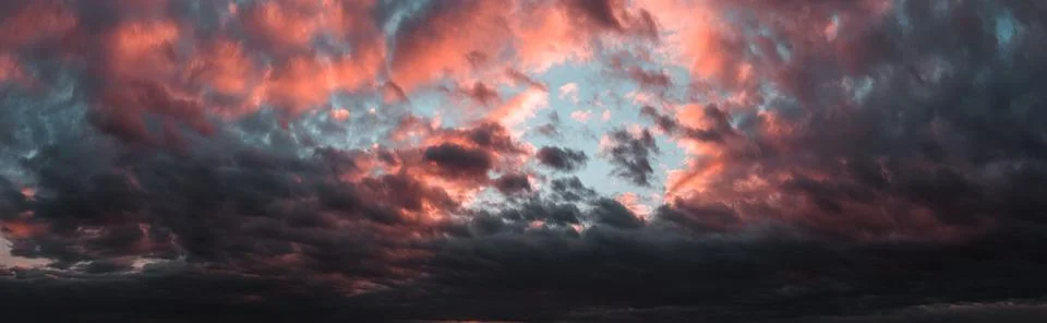 Dramatic dark sunset. Panorama of dark rain clouds in the evening. A rich red Stock Photos