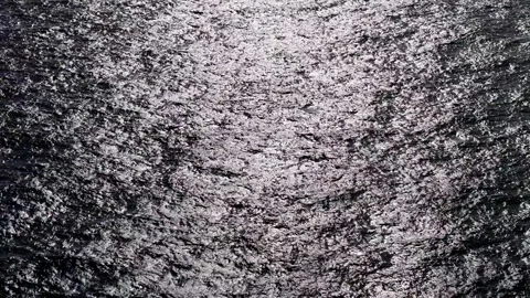 Dramatic dark texture with sunlight glistening on empty ocean water Stock Footage 263183686