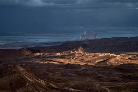 Dramatic desert coastline landscape with storm clouds over calm sea Photos