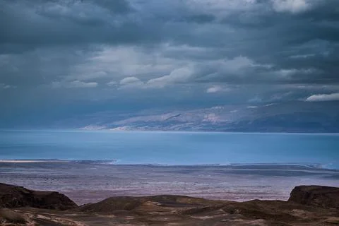 Dramatic desert coastline landscape with storm clouds over calm sea Stock Photos