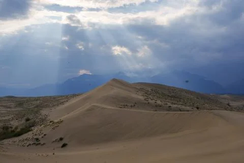 Dramatic desert dunes under sunbeams and cloudy sky Stock Photos