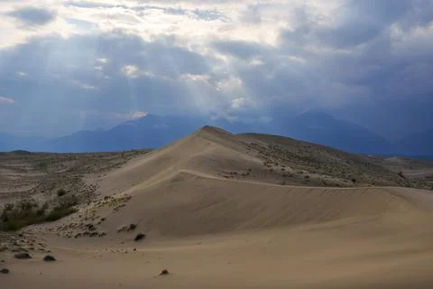 Dramatic desert dunes under sunbeams and cloudy sky Stock Photos
