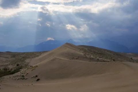 Dramatic desert dunes under sunbeams and cloudy sky Foto stock