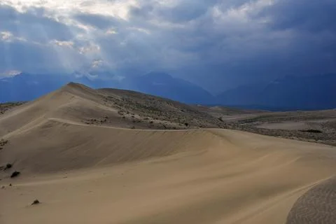 Dramatic desert dunes under sunbeams and cloudy sky Stock Photos