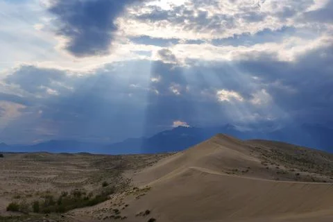 Dramatic desert dunes under sunbeams and cloudy sky Stock Photos