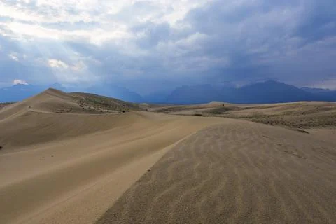 Dramatic desert dunes under sunbeams and cloudy sky Stock Photos