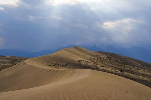 Dramatic desert dunes under sunbeams and cloudy sky Stock Photos