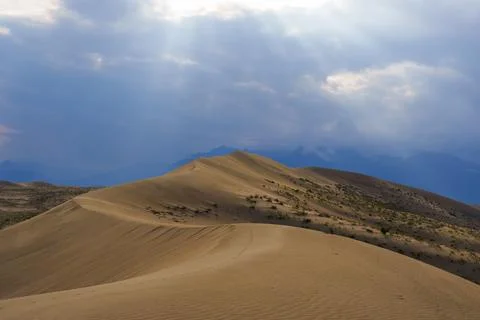 Dramatic desert dunes under sunbeams and cloudy sky Stock Photos