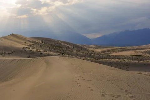 Dramatic desert dunes under sunbeams and cloudy sky Stock Photos