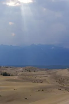 Dramatic desert dunes under sunbeams and cloudy sky Stock Photos
