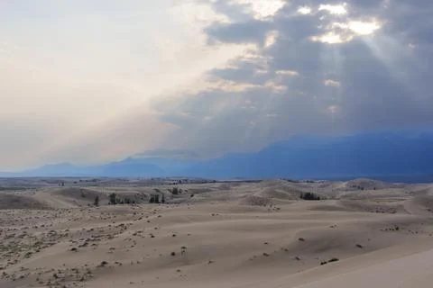 Dramatic desert dunes under sunbeams and cloudy sky Stock Photos