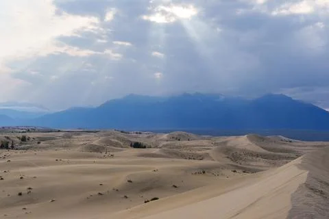 Dramatic desert dunes under sunbeams and cloudy sky Stock Photos