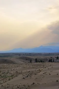 Dramatic desert dunes under sunbeams and cloudy sky Stock Photos