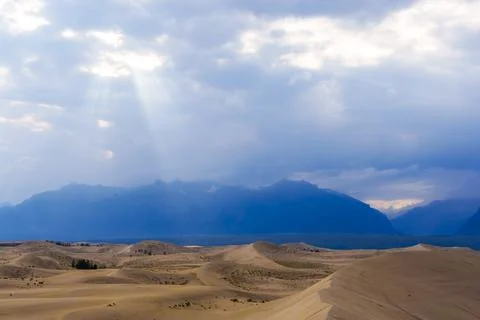 Dramatic desert dunes under sunbeams and cloudy sky Stock Photos