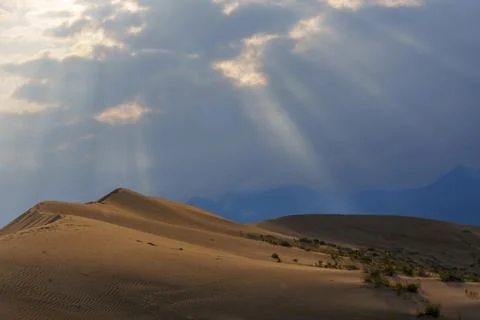 Dramatic desert dunes under sunbeams and cloudy sky Stock Photos