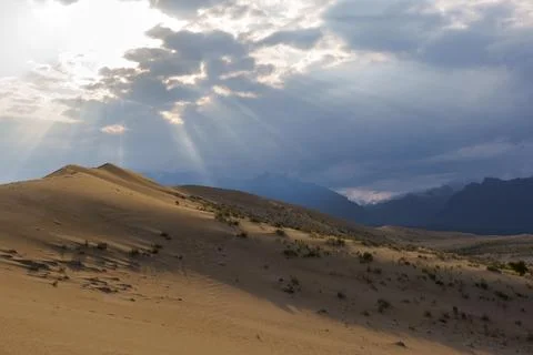 Dramatic desert dunes under sunbeams and cloudy sky Stock Photos