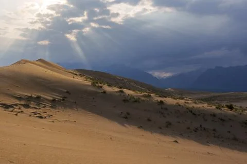 Dramatic desert dunes under sunbeams and cloudy sky Stock Photos