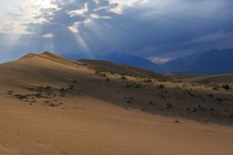 Dramatic desert dunes under sunbeams and cloudy sky Stock Photos