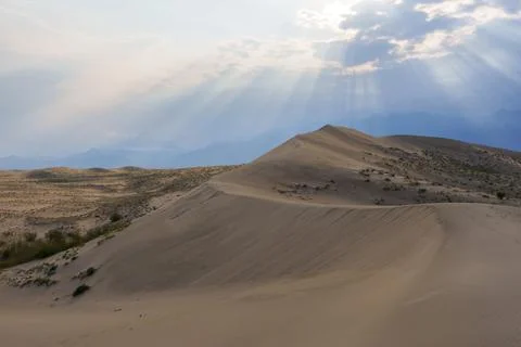 Dramatic desert dunes under sunbeams and cloudy sky Stock Photos