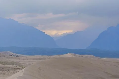 Dramatic desert dunes under sunbeams and cloudy sky Stock Photos