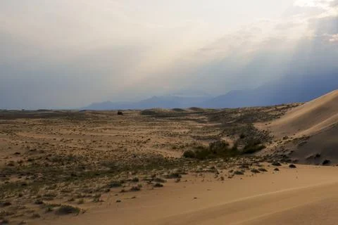 Dramatic desert dunes under sunbeams and cloudy sky Stock Photos