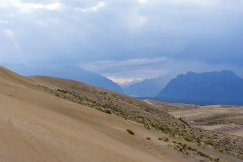 Dramatic desert dunes under sunbeams and cloudy sky Foto stock