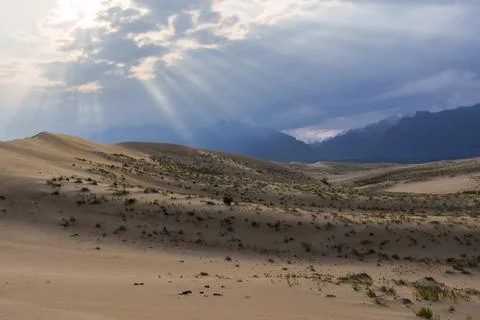 Dramatic desert dunes under sunbeams and cloudy sky Stock Photos