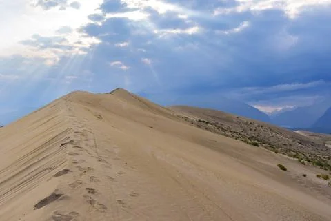 Dramatic desert dunes under sunbeams and cloudy sky Stock Photos