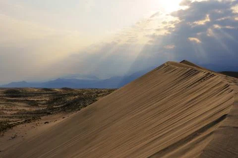 Dramatic desert dunes under sunbeams and cloudy sky Foto stock