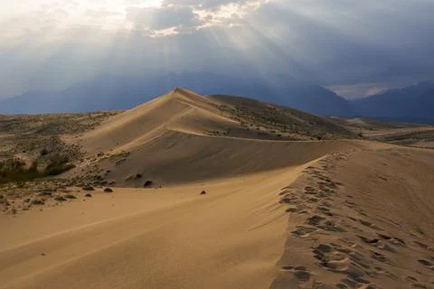 Dramatic desert dunes under sunbeams and cloudy sky Stock Photos